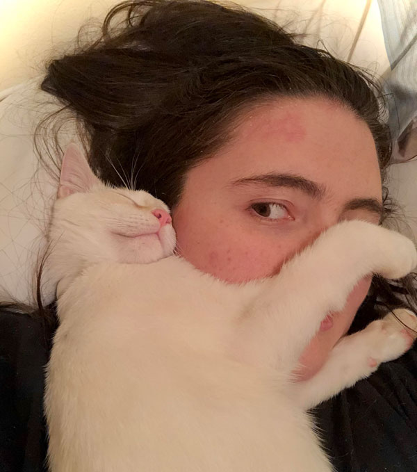 white cat sleeping on woman's face